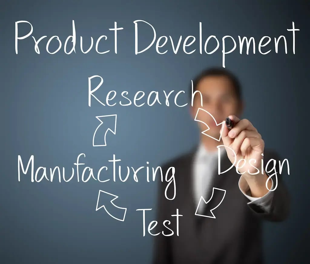 an engineer writing the steps of the lifecycle of product development, which is circular.  first is research, then design, into test, and manufacturing which goes back to research.