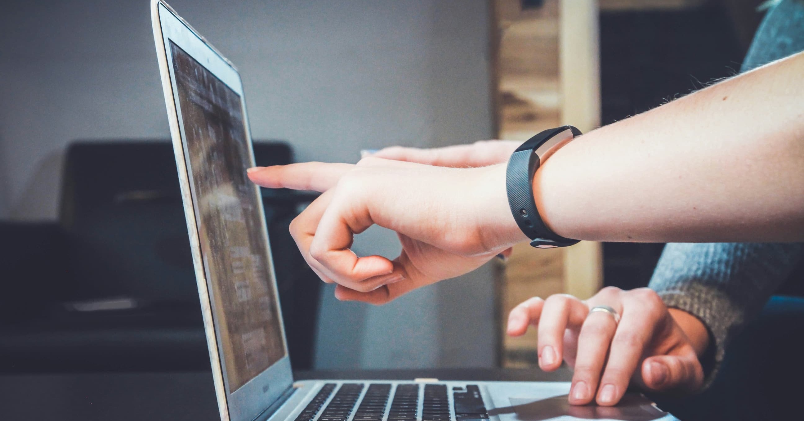 a person pointing at a laptop screen
