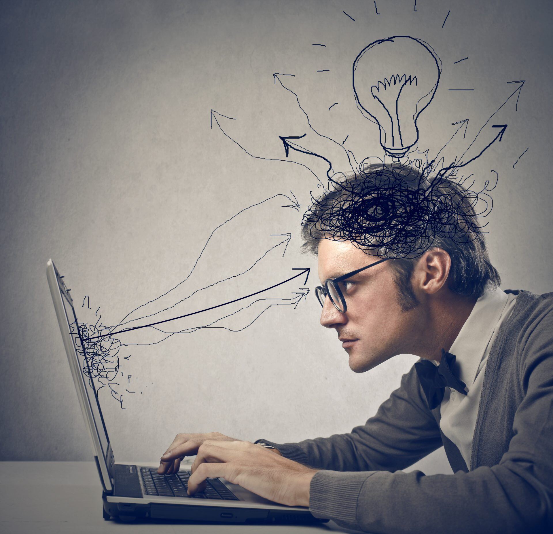 man staring at computer, with a cartoon lightbulb above his head