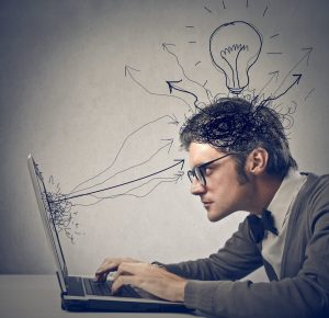 man staring at computer, with a cartoon lighbulb above his head